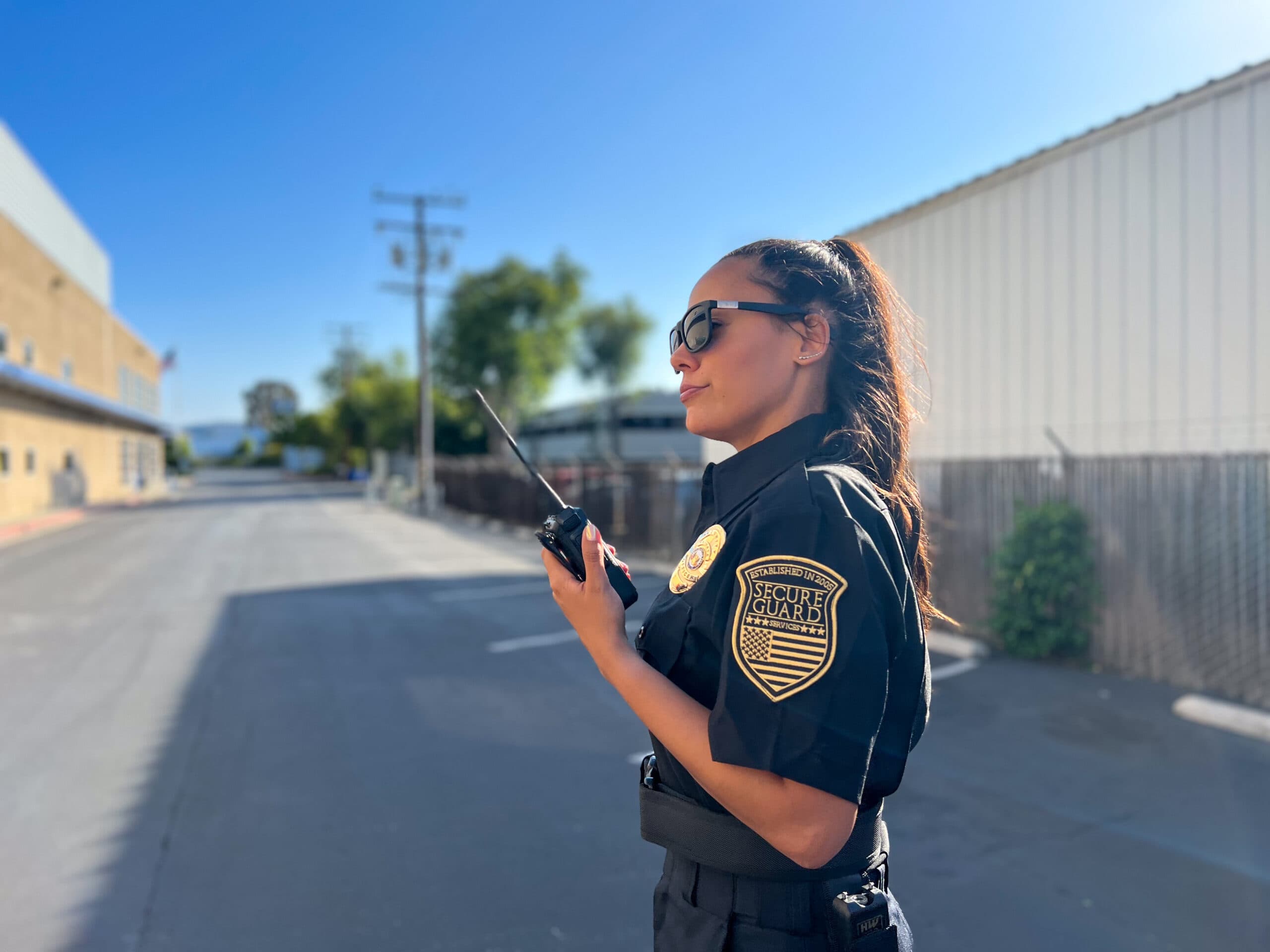 A security team using modern communication tools including smart radios, body cameras, and smartwatches while monitoring a live feed on a tablet during patrol.