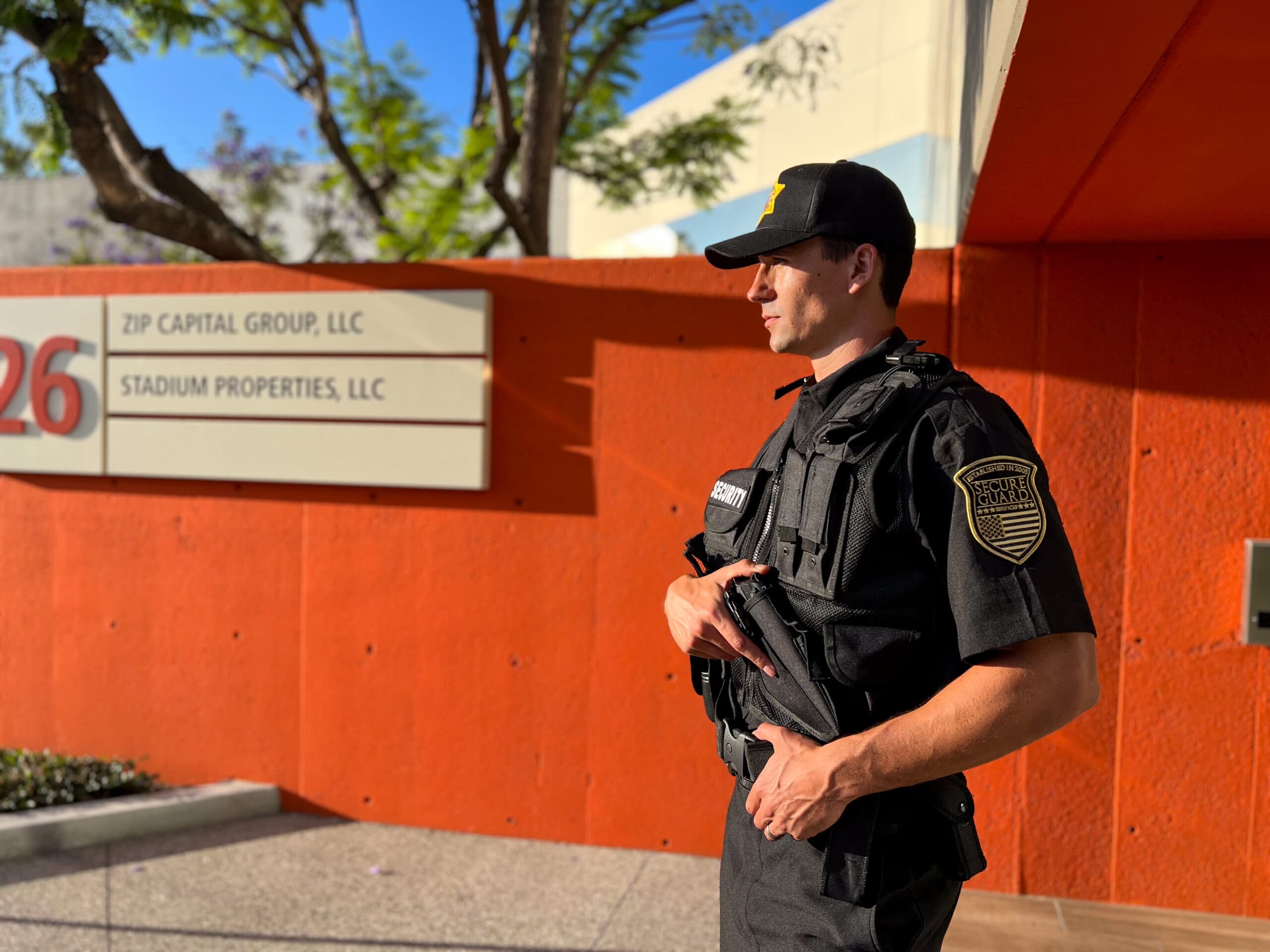 Professional security guard in uniform standing alert outside a commercial building, providing safety and surveillance for Secure Guard Security Services.