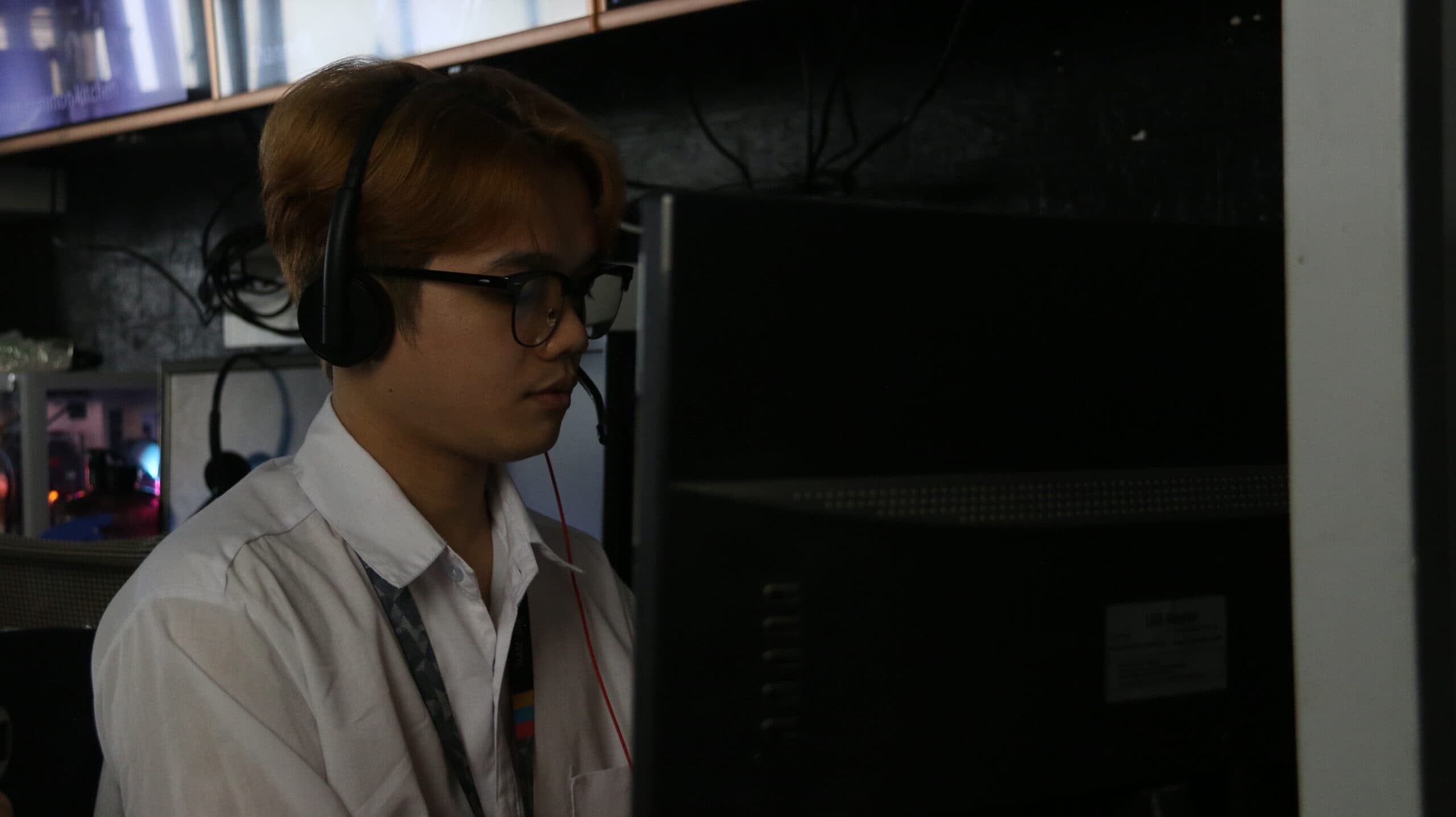 A security support staff member wearing a headset works attentively at a computer station, monitoring and assisting in real-time.
