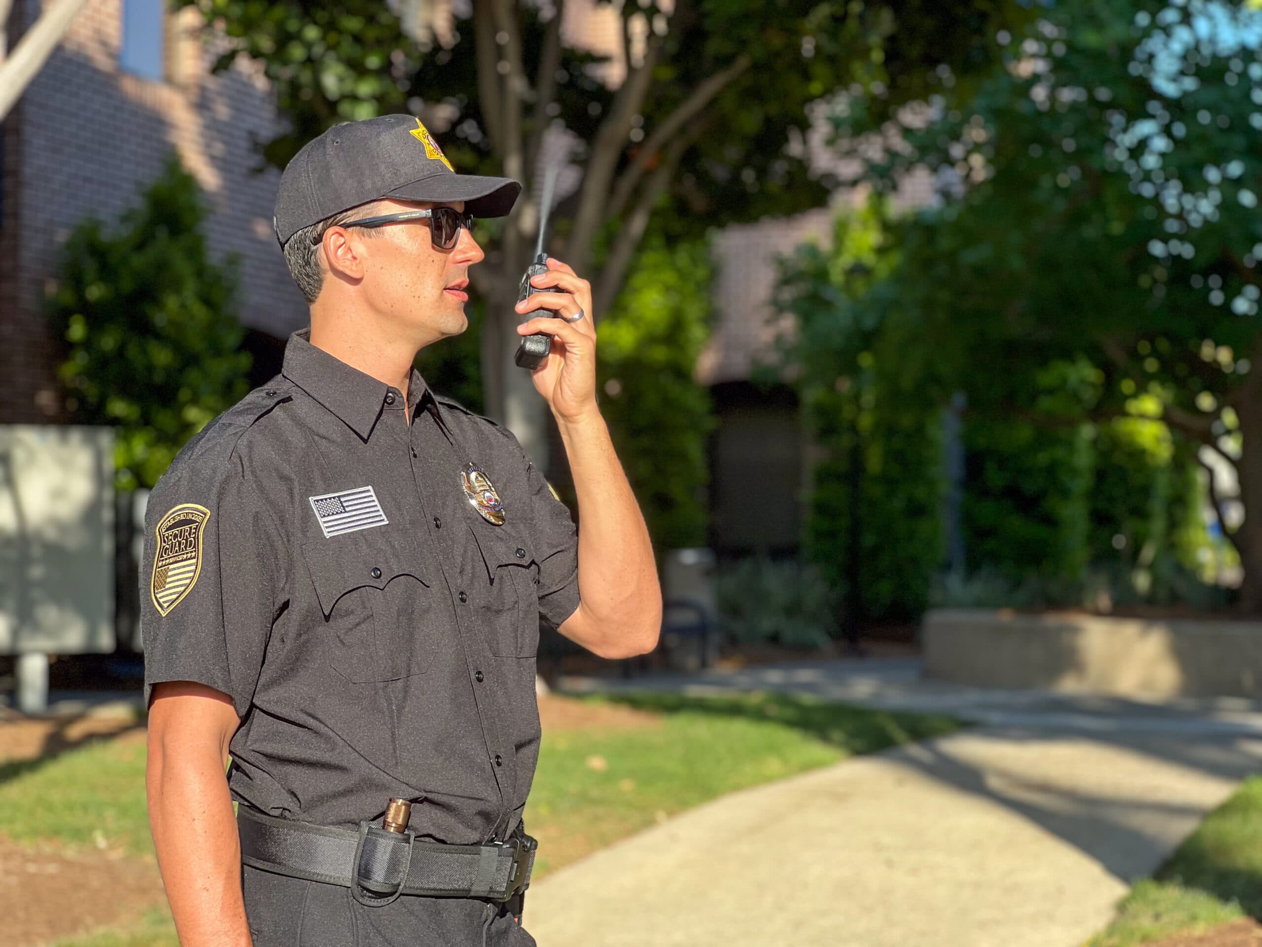 Security guard in uniform patrolling a property with a two-way radio, representing trustworthy security companies committed to safety and protection.
