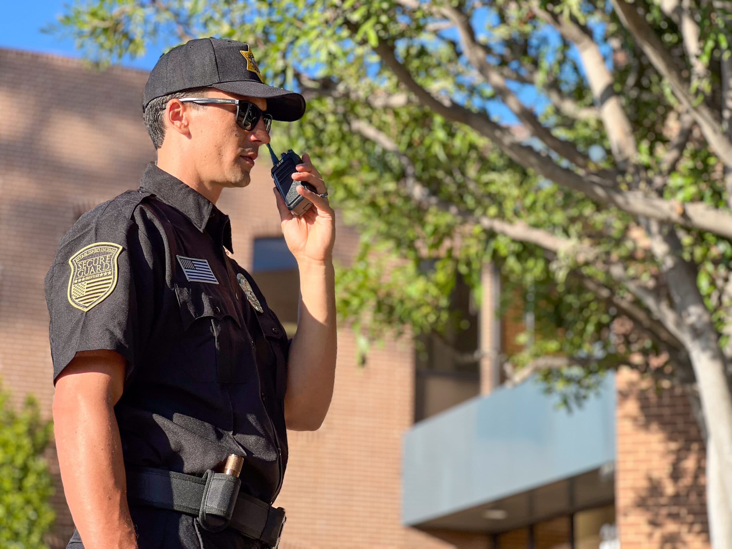 Security guard conducting outdoor patrol with a two-way radio at an apartment complex in San Jose, ensuring tenant safety and property protection.
