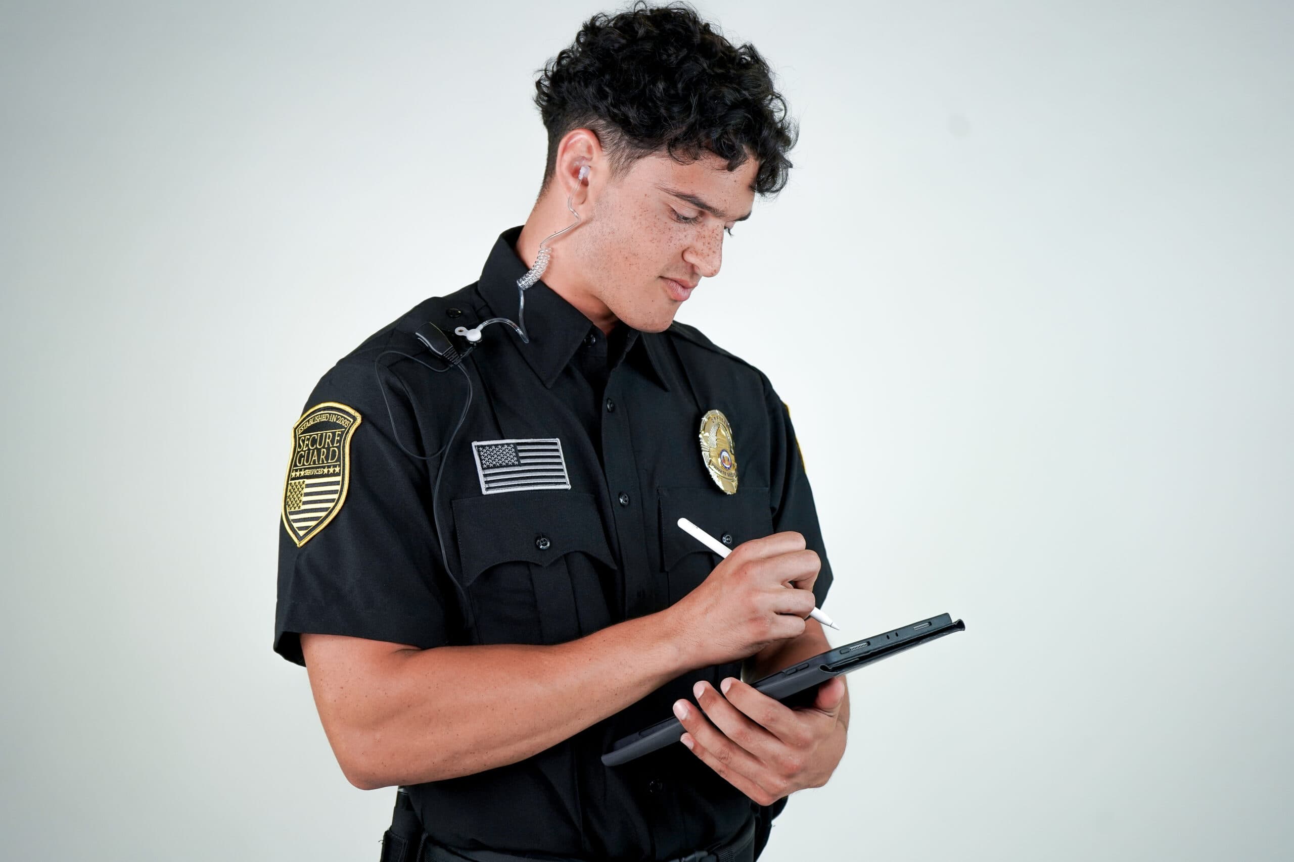 Modern security guard using digital guard management software on a tablet to log patrol activity, demonstrating technology-driven security operations in 2025.