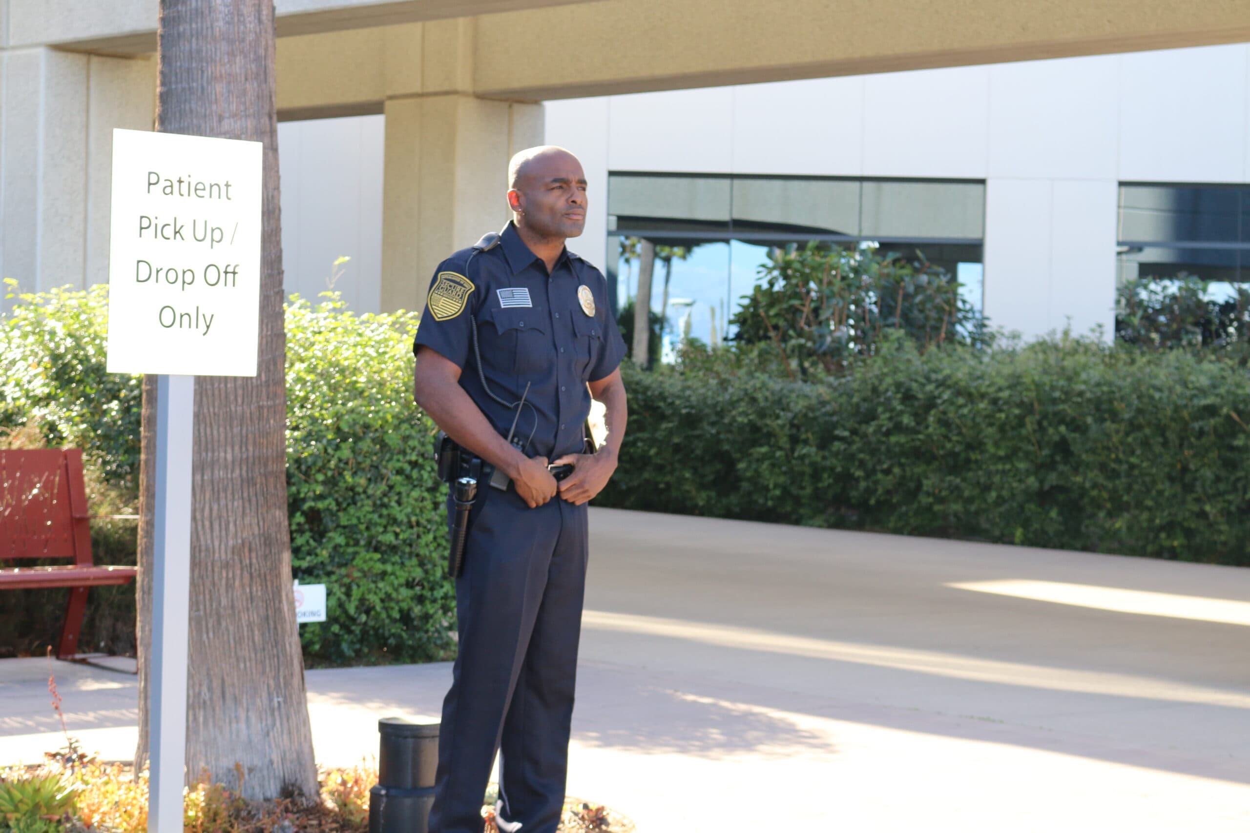 Professional healthcare security guard standing outside a medical facility in California, monitoring patient pickup and drop-off areas to ensure safety and access control.