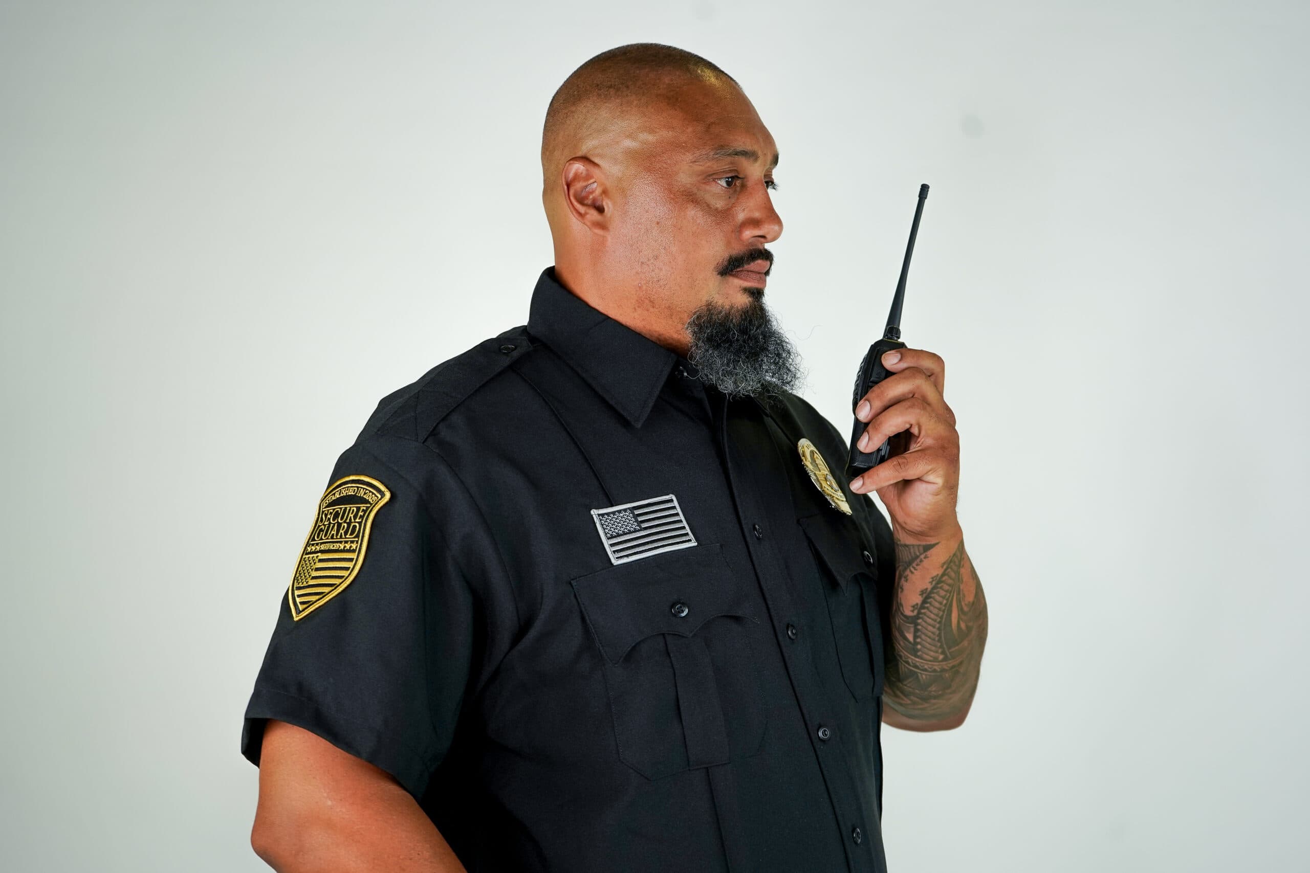 Professional security guard using two-way radio during routine safety inspection, demonstrating proactive maintenance checks and preventative security measures
