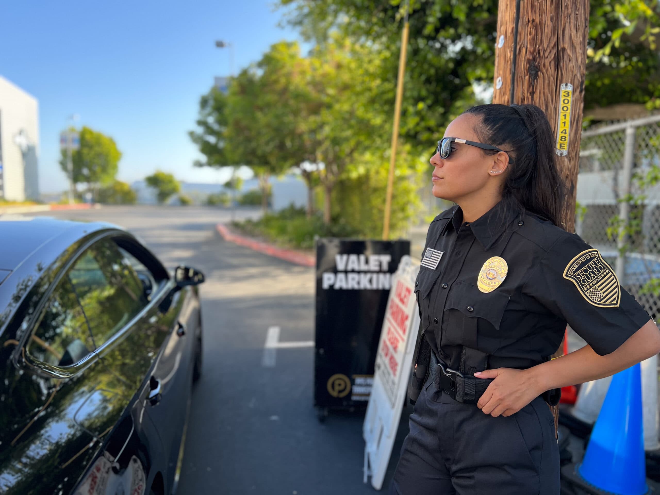 Licensed security guard with guard card on duty near a parking area, monitoring surroundings and assisting with site security operations