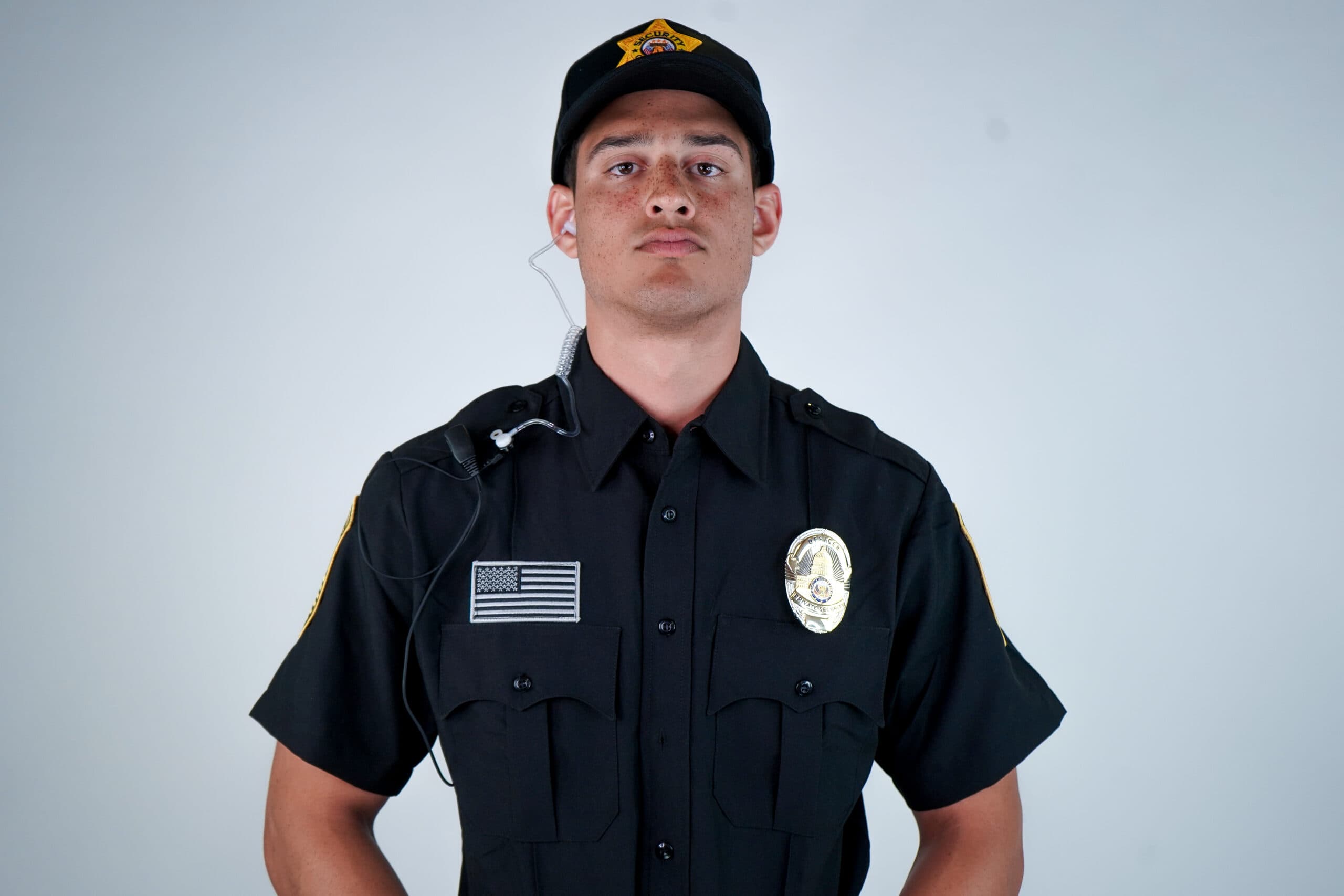 Professional hotel security guard standing alert in uniform with a communication earpiece, representing proactive hotel security measures, guest safety, and liability risk management in 2026.